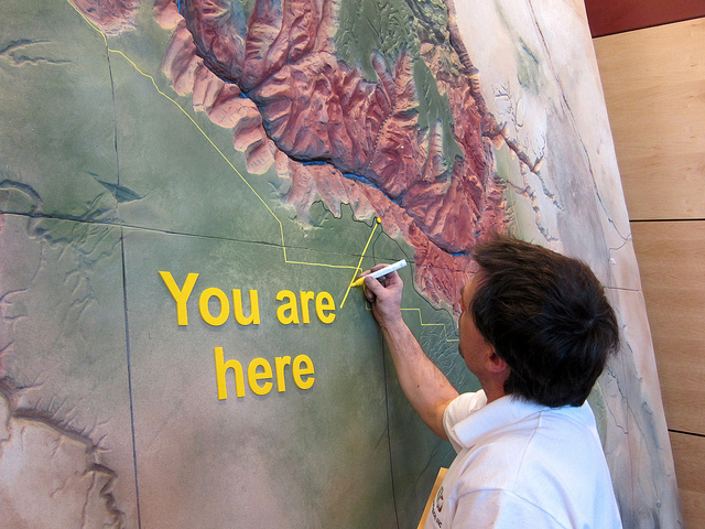 Man writing "you are here" on map of the Grand Canyon