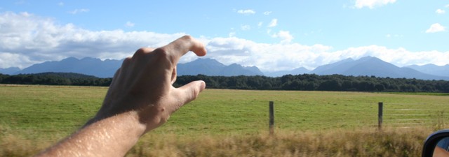 A hand squishing a mountain range's head